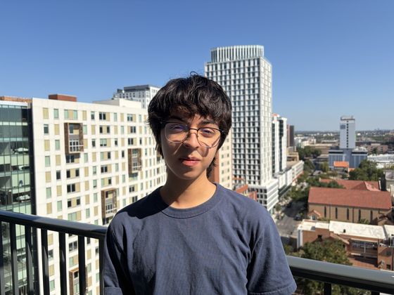 Ethan on a balcony with a city skyline behind him