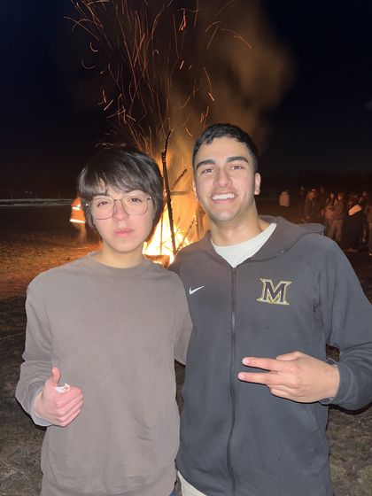 Ethan and a friend in front of a bonfire at night