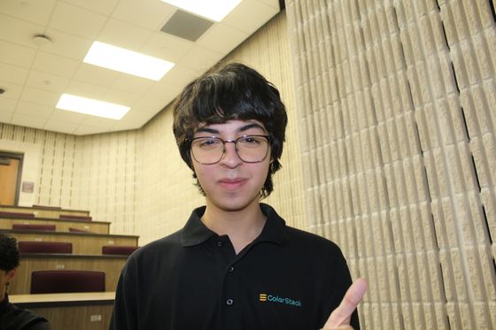 Ethan in a ColorStack polo pointing in a lecture hall