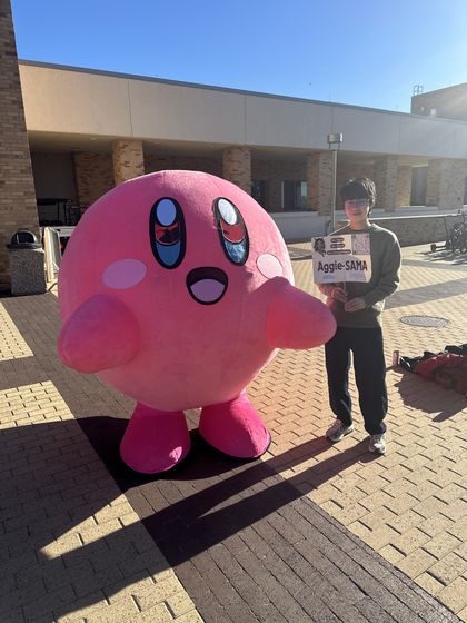 Ethan on campus next to a giant Kirby mascot
